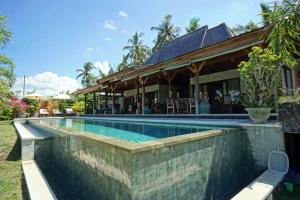 a swimming pool in front of a house at Villa Taman Kanti in Ubud