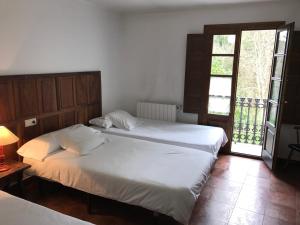 two twin beds in a room with a window at La Casa Del Reloj in Molinaseca
