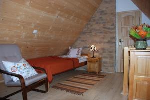 1 dormitorio con 1 cama y 1 silla en el ático en Apartament Lux Czerwone Korale, en Kościelisko