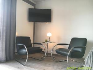 a room with two chairs and a table with a tv on the wall at petite maison in Lüneburg