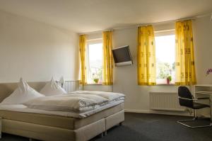 a bedroom with a bed with yellow curtains and a tv at Hotel zum Rücking in Northeim