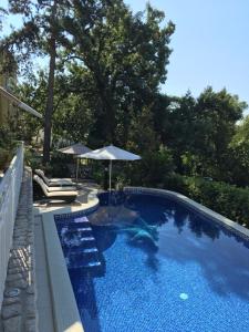 una piscina con sombrilla, sillas y sombrilla en Guest House Villa Dagmar en Crikvenica