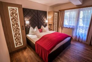 a bedroom with a large bed with a red blanket at Hotel-Appartement Ferienhof in Gerlos