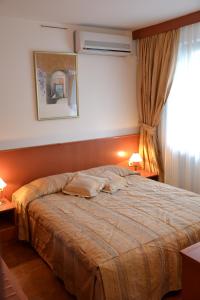 a bed in a bedroom with two lamps and a window at Hotel Dva Bisera in Ohrid