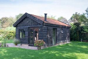 a small wooden house with a green lawn at Vakantiehuisje met bedstee in Diever