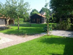 a house with a green yard with trees and a driveway at Vakantiehuisje met bedstee in Diever