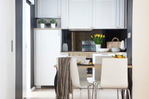 kuchnia z białymi szafkami, stołem i krzesłami w obiekcie Premium Class Apartments w Zagrzebiu