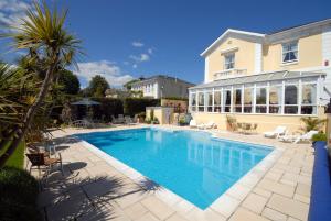 a swimming pool in front of a house at Riviera Lodge Hotel in Torquay