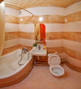 a bathroom with a tub and a toilet and a sink at Poltava Green Apartments in Poltava