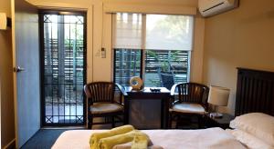 una camera da letto con un letto, una scrivania e delle sedie di Bali Studio a Darwin