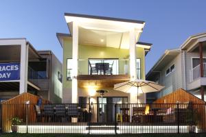 a house with a balcony with an umbrella and tables at Lakeside Deck House in Mackay