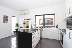 a kitchen with white cabinets and a black counter top at Lakeside Deck House in Mackay
