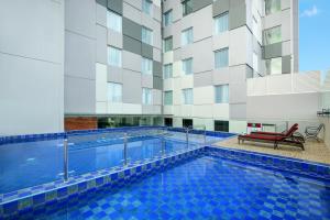 a swimming pool in front of a building at Ibis Styles Makassar Sam Ratulangi in Makassar