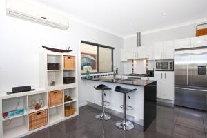 a kitchen with white cabinets and a stainless steel refrigerator at Lakeside Deck House in Mackay