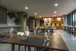a restaurant with wooden tables and chairs with glasses on them at deVloft hotel Korat in Nakhon Ratchasima