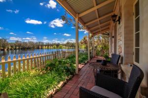 a porch with a table and chairs and a view of the water at Stonewell Cottages and Vineyards in Tanunda
