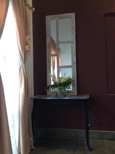 a mirror on a table with a vase of flowers at The Patio Yogya in Yogyakarta