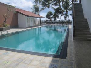 une grande piscine bleue à côté d'un bâtiment dans l'établissement Oasis Ayurveda Beach Hotel, à Ambalangoda