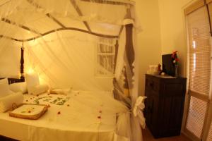 ein Schlafzimmer mit einem weißen Bett mit Baldachin in der Unterkunft Oasis Ayurveda Beach Hotel in Ambalangoda