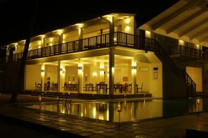 ein nachts beleuchtetes Gebäude mit einem Pool in der Unterkunft Oasis Ayurveda Beach Hotel in Ambalangoda