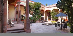 un patio al aire libre con mesas, sillas y sombrillas en Casona de la Republica Hotel Boutique & SPA, en Querétaro