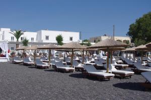 a group of lounge chairs and umbrellas on a beach at La Mer Deluxe Hotel & Spa in Kamari