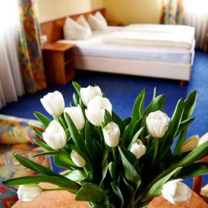 a vase of white flowers in a room with a bed at Hotel-Cafe Rathaus in Bad Abbach