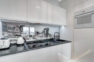 a kitchen with white cabinets and a sink at Luksusowy Apartament Good Morning Gdansk in Gdańsk
