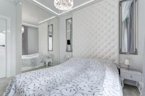 グダニスクにあるLuksusowy Apartament Good Morning Gdanskの白いベッドルーム(大型ベッド1台、鏡付)