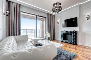a white living room with a white couch and a fireplace at Luksusowy Apartament Good Morning Gdansk in Gdańsk