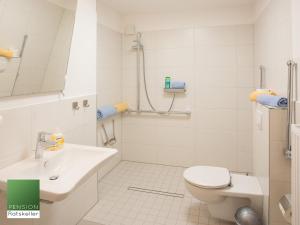 a white bathroom with a toilet and a sink at Pension Ratskeller in Hagenow