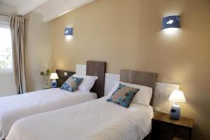 two beds in a room with two lamps on the wall at Avion B&B in Cagliari