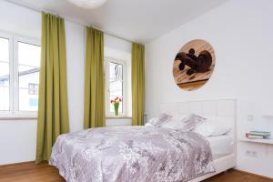 a white bedroom with a bed and green curtains at Amedeo Zotti Residence Salzburg in Salzburg
