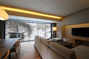 a living room with a couch and a large window at Aya Niseko in Niseko