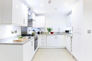 ボアハムウッドにあるBorehamwood - Luxury 2 bed 2 bath apartmentの白いキッチン(白いキャビネット、電化製品付)