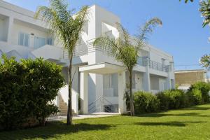 a white building with palm trees in front of it at Blumarine Residence Club in Ostuni