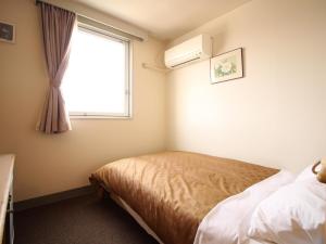 a bedroom with a bed and a window at Hotel LC Gifu Hashima in Hashima
