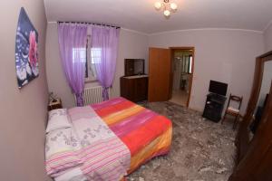 サン・ヴィート・キエティーノにあるLa Scogliera B&Bのベッドルーム(カラフルなベッド1台、紫色のカーテン付)