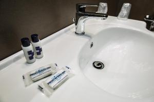 a bathroom sink with toothbrushes and other items on it at Mediterranea Hotel & Convention Center in Salerno