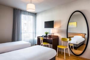 ヴァンヴにあるアパートホテル アダージョ アクセス パリ ヴァンヴ ポルト ド シャティヨンのベッド2台と鏡が備わるホテルルームです。