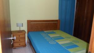 a small bedroom with a bed and a night stand at SUN & SURF in Aljezur