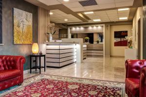 a lobby with red leather chairs and a counter at Albergo Papillon in Cazzago San Martino