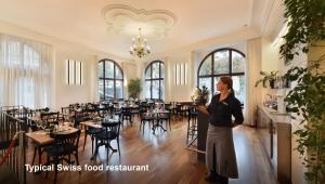 a woman standing in front of a dining room at Hotel National Bern in Bern