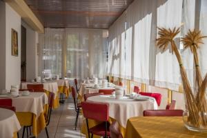 a dining room with tables and chairs with yellow tablecloths at Hotel Meris in Milano Marittima