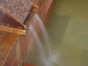 a stream of water coming out of a brick wall at Toya Gokirakutei in Lake Toya