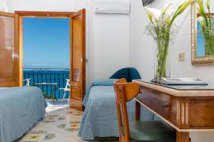 a bedroom with a desk and a table with a vase on it at Hotel Pupetto in Positano