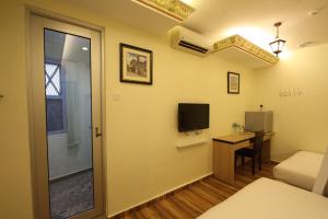 a room with a bed and a desk with a television at Shamrock Guest House II in Ipoh