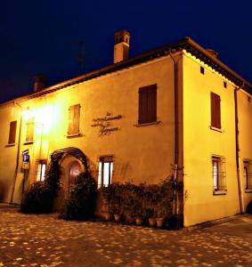 un bâtiment blanc avec un panneau sur lui la nuit dans l'établissement Hotel Locanda Di Bagnara, à Bagnara di Romagna