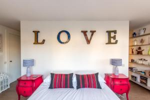 a bedroom with two red end tables and the word love on the wall at Boat Lake in Thorpeness