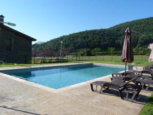 a swimming pool with chairs and an umbrella at Mas El Ferrés in Joanetes